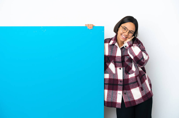 Молодая женщина смешанной расы с большим голубым плакатом на белом фоне смеется - Фото, изображение