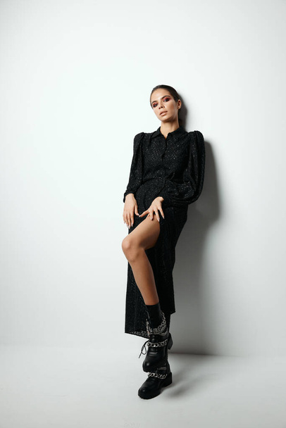 aantrekkelijke brunette met heldere make-up modieuze moderne kleding zwarte laarzen - Foto, afbeelding