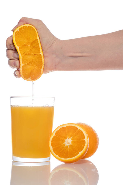 Hand squeezed fresh orange juice into a glass isolated on white background. - Photo, Image