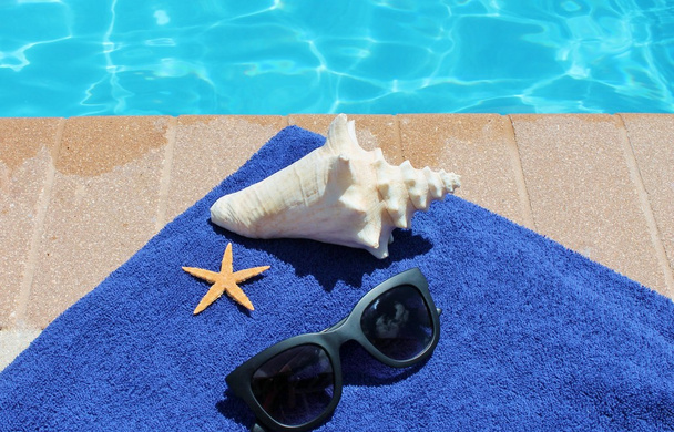 Vacaciones junto a la piscina pintoresca piscina gafas de sol de verano concha toalla estrella de mar
 - Foto, imagen