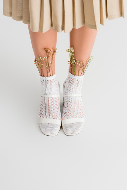 bijgesneden weergave van jonge vrouw in sokken met bloemen en hakken schoenen staan op wit - Foto, afbeelding