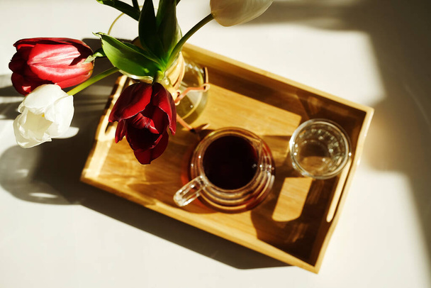 Spécialité esthétique du café. Café fraîchement infusé servi sur plateau en bambou, table blanche ensoleillée. Fleurs en carafe de café - Photo, image