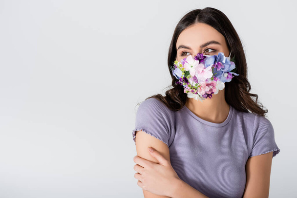 jeune femme en masque médical avec des fleurs isolées sur blanc - Photo, image