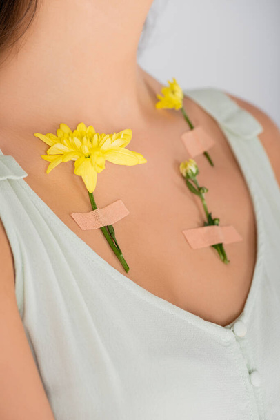 przycięty widok tynków z żółtymi kwiatami na ciele kobiety odizolowanej na białym - Zdjęcie, obraz