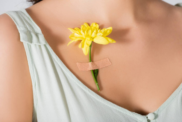 καλλιεργημένη άποψη του κίτρινου λουλουδιού με γύψο στο σώμα της νεαρής γυναίκας - Φωτογραφία, εικόνα