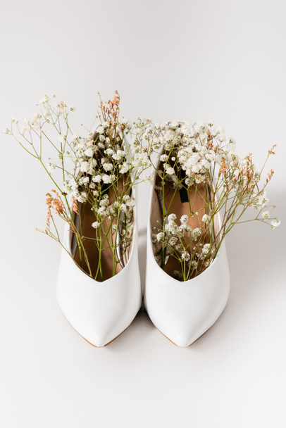 hakken schoenen met bloeiende gypsophila bloemen op wit  - Foto, afbeelding
