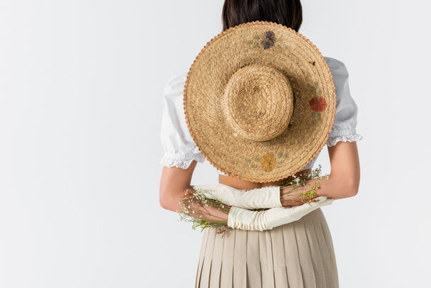 白い背後に孤立した花や藁帽子をかぶった手袋の若い女性の部分的なビュー  - 写真・画像