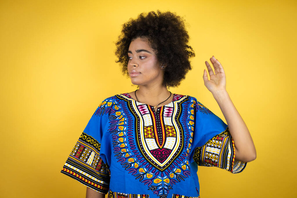 Afrikaans amerikaanse vrouw dragen Afrikaanse kleding over gele achtergrond met een gelukkig gezicht staande en glimlachend met een zelfverzekerde glimlach tonen tanden - Foto, afbeelding