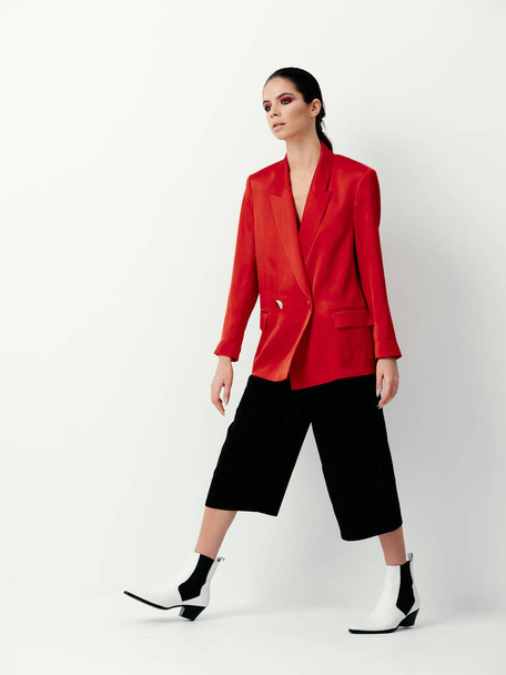 brunette in rode jas heldere make-up glamor decoratie lichte achtergrond - Foto, afbeelding