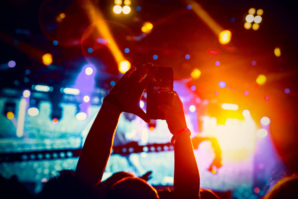 Homem tira uma foto do show na sala de concertos usando um smartphone - Foto, Imagem