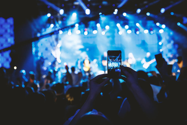 Main avec le smartphone allumé pour enregistrer ou prendre des photos pendant le concert en direct - Photo, image