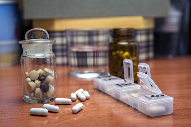Vieja botella de pastillas junto con algunas pastillas por encima de una mesa de madera
 - Foto, imagen