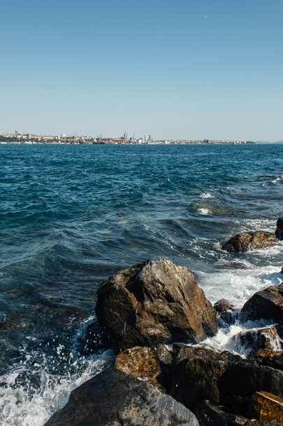 Kamienie w wodzie morskiej z błękitnym niebem na tle  - Zdjęcie, obraz