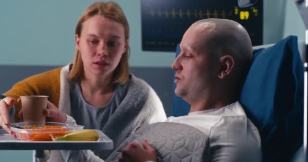 Ehefrau gibt Ehemann Essen in onkologischem Krankenhaus - Filmmaterial, Video
