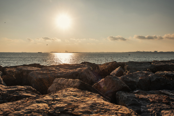 Malowniczy widok kamieni na wybrzeżu morza podczas zachodu słońca - Zdjęcie, obraz