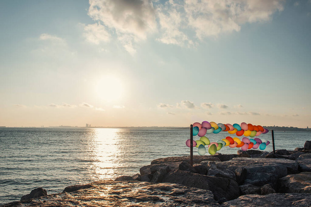 Palloncini colorati sulla costa del mare durante il tramonto  - Foto, immagini