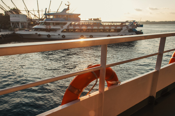 Lifebuoy on ship railing with sea during sunset at background, Isztambul, Törökország  - Fotó, kép
