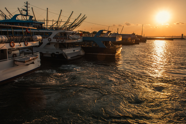 Лодки на морской воде с солнцем в небе на закате, Стамбул, Турция  - Фото, изображение