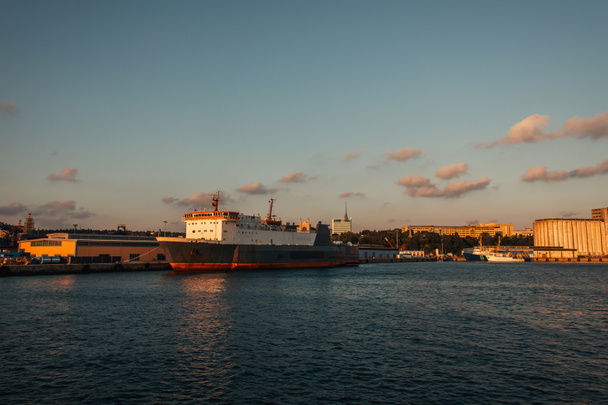 Statek towarowy na morzu i budynki na wybrzeżu Stambułu podczas zachodu słońca, Turcja  - Zdjęcie, obraz