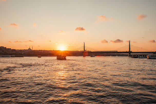 Scenic view of boast in sea, Golden horn metro bridge and sunset sky in Istanbul, Turkey  - Photo, Image