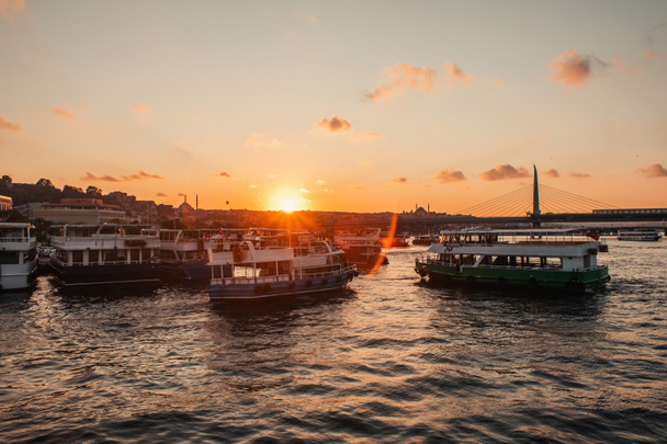Boten in zee met zonsondergang zon en Golden Horn metro brug op de achtergrond, Istanbul, Turkije  - Foto, afbeelding