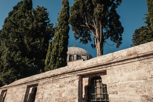Steinmauer mit eingezäunten Fenstern und hohen Bäumen in der Nähe der Mihrimah Sultan Moschee, Istanbul, Türkei - Foto, Bild