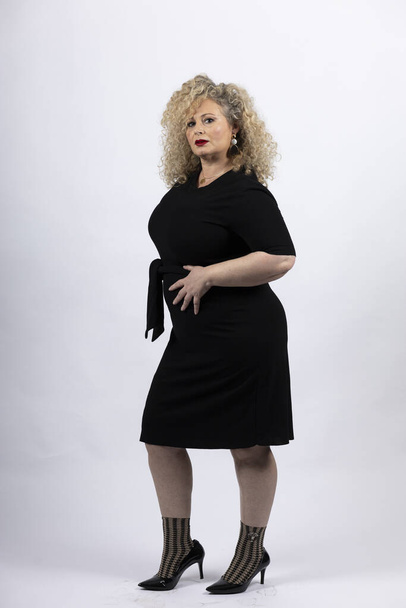 A vertical shot of a mature plus-size female model wearing a black dress on a white background - Foto, afbeelding