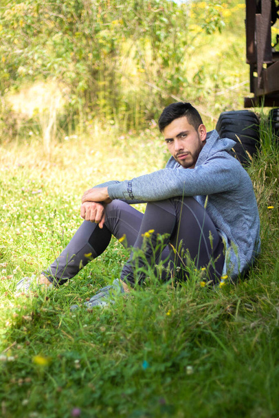 A handsome sporty man sitting and relaxing in nature - Fotoğraf, Görsel