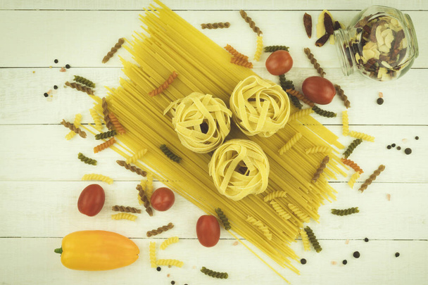 Spaghettis crus et pâtes avec espace pour le texte sur un fond en bois. Sélection de pâtes séchées mélangées sur fond en bois - Photo, image