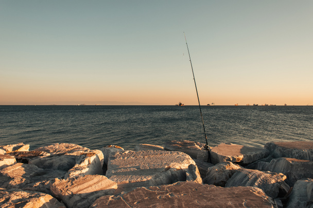 caña de pescar en piedras en la orilla del mar - Foto, imagen