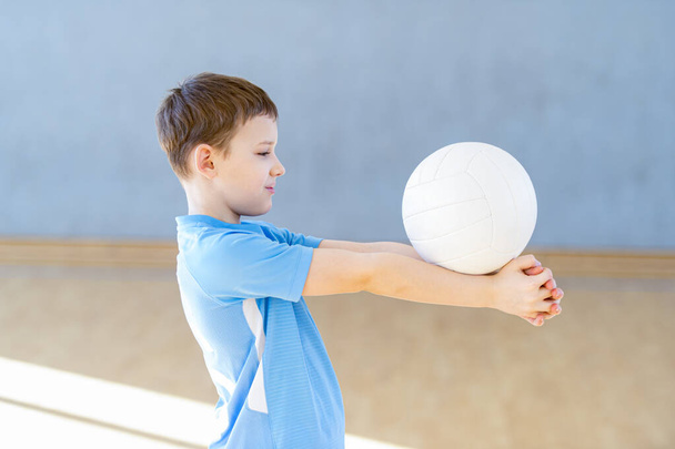 Un écolier jouant au volley-ball dans une leçon d'éducation physique. Retour à l'école en toute sécurité pendant la pandémie concept - Photo, image