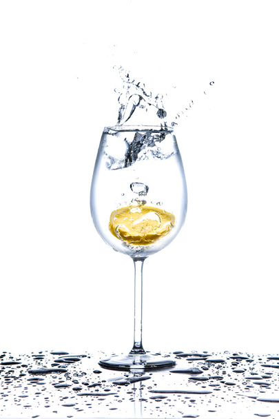 Lemon splashing into glass of water on white background - Foto, immagini