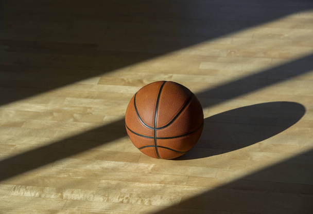 Basketball sur parquet avec éclairage naturel. Concept d'entraînement en ligne - Photo, image