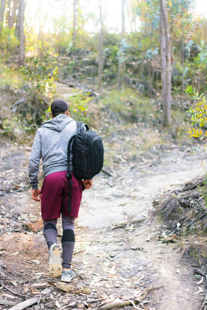 A back view of a sportsman walking with a black backpack after finishing the workout in nature - Foto, Imagem