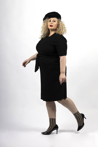 A vertical shot of a mature plus-size female model wearing a black dress on a white background - Photo, Image