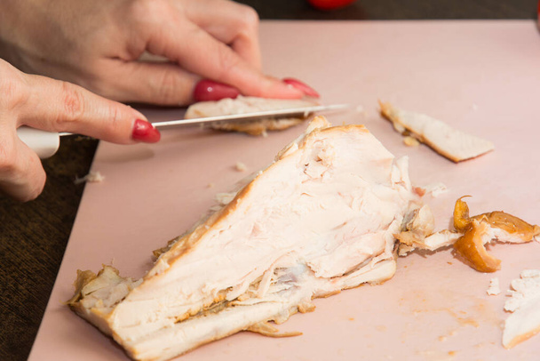 επιλεκτική εστίαση. γυναίκα κόβει βραστό στήθος κοτόπουλου σε μικρά κομμάτια. σπιτικό πίτσα μαγείρεμα έννοια. - Φωτογραφία, εικόνα