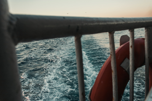 vista de cerca de la cerca y la boya salvavidas en el buque flotando en el mar - Foto, imagen
