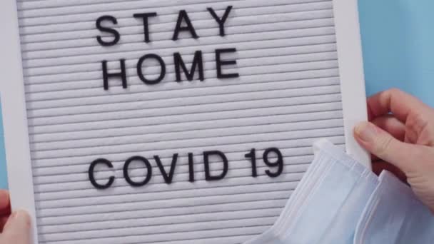 Μείνετε σπίτι και COVID-19 υπογράψει στον πίνακα μηνυμάτων με μια σπιτική μάσκα προσώπου. - Πλάνα, βίντεο