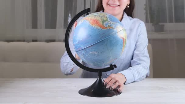 Самка смотрит на модель земного шара. Белая стена пустой фон. - Кадры, видео
