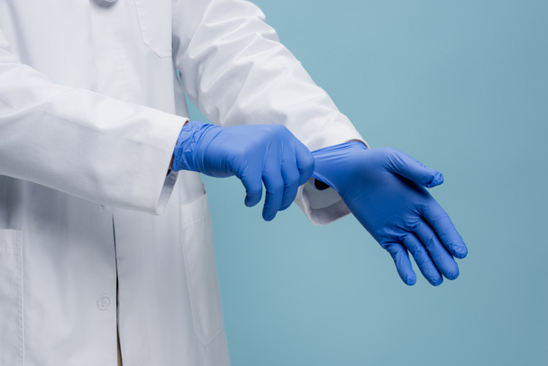 обрезанный вид доктора в латексных перчатках, изолированных на синий - Фото, изображение