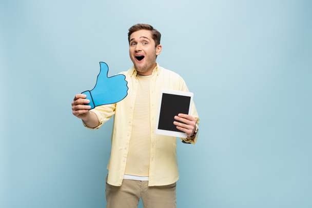 homem surpreso na camisa segurando papel como e tablet digital com tela em branco isolado em azul - Foto, Imagem