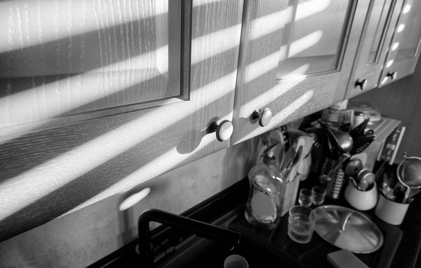 Italia, Sicilia, gabinetes de cocina de madera con rayos de sol desde la ventana en la mañana - Foto, imagen