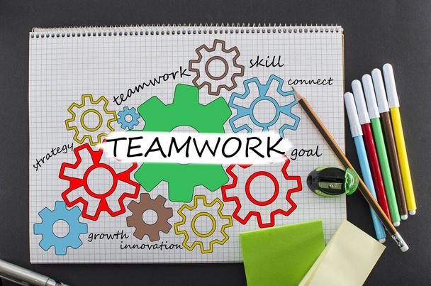 Teamwork concept. Bovenaanzicht van kleurrijke tekening van tandwielen in notitieblok met verschillende kleuren pennen met teamwork inscriptie. - Foto, afbeelding