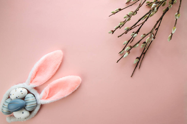 Easter, spring flat lay with colorful eggs, bunny ears and willow branches on a pastel pink background. Copy space - Photo, Image