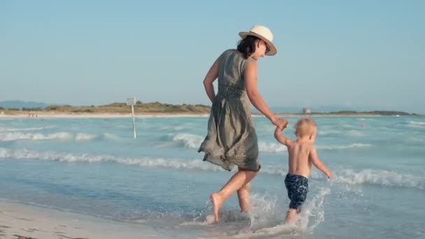Kobieta ciesząca się rodzinnym weekendem nad morzem. Matka i syn spacerujący po brzegu morza. - Materiał filmowy, wideo