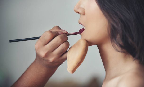 Makeup artist applies red lipstick . Beautiful woman face. Hand of make-up master, painting lips of young beauty model girl . Make up in process - Фото, изображение