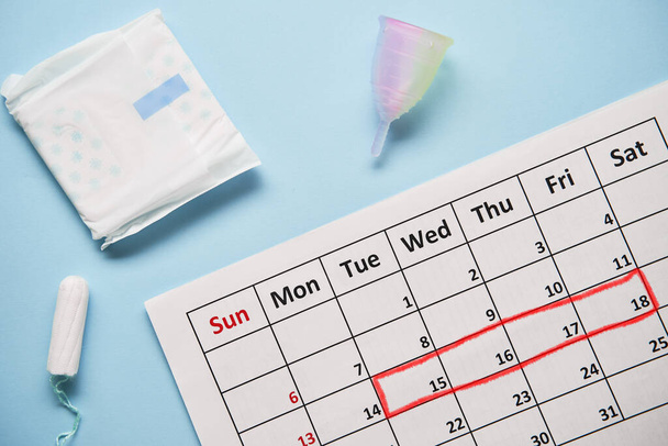 Calendario con tamponi di cotone e coppetta mestruale. Giorni critici per la donna e protezione dell'igiene - Foto, immagini