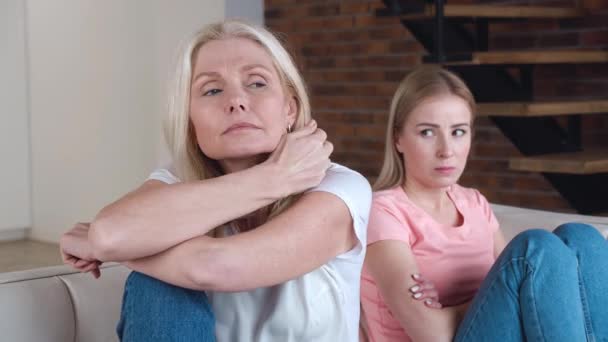 Senior Mother and her young adult daughter turn back on sofa after conflict. Resentful daughter and mature mother feel upset having misunderstanding. - Footage, Video
