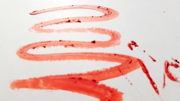 Krásné jasně červené šmouhy rtěnky na bílém pozadí, rozbité části rtěnky, textura. Kosmetika pro krásu. Kosmetika, detailní záběr, 4K video - Záběry, video