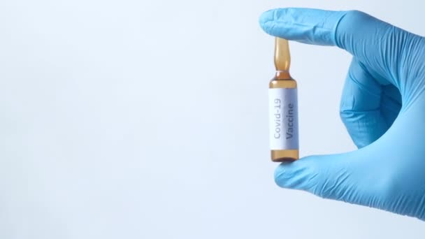 mão em luvas de látex segurando vacina ampola de vidro, com espaço de cópia  - Filmagem, Vídeo
